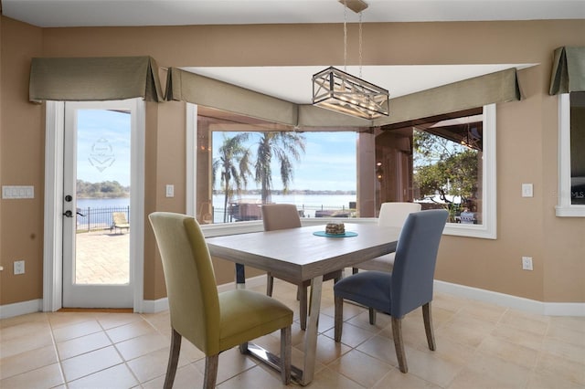 tiled dining area with plenty of natural light, a water view, and an inviting chandelier