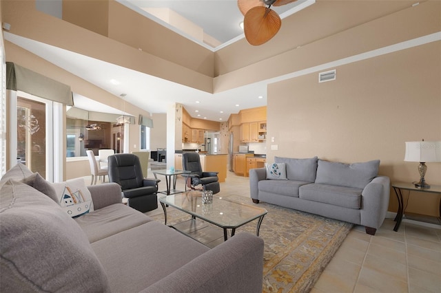 living room with a towering ceiling, ceiling fan, and light tile patterned flooring