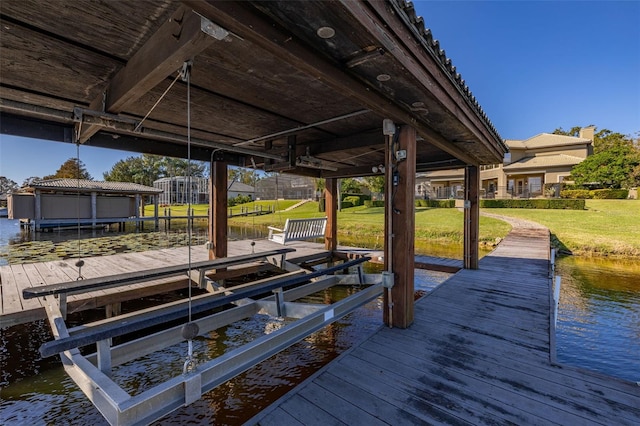 view of dock with a lawn and a water view