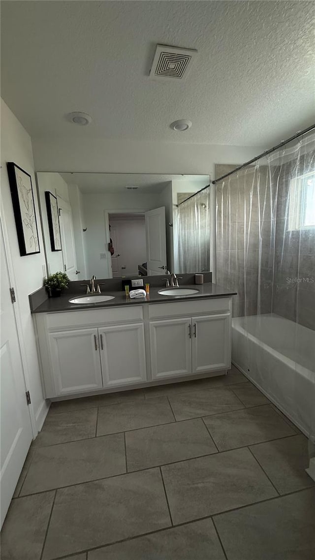 bathroom featuring vanity, tiled shower / bath combo, tile patterned floors, and a textured ceiling