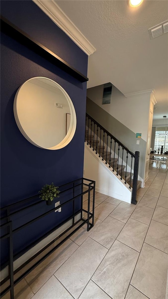 staircase featuring a textured ceiling, tile patterned flooring, and ornamental molding