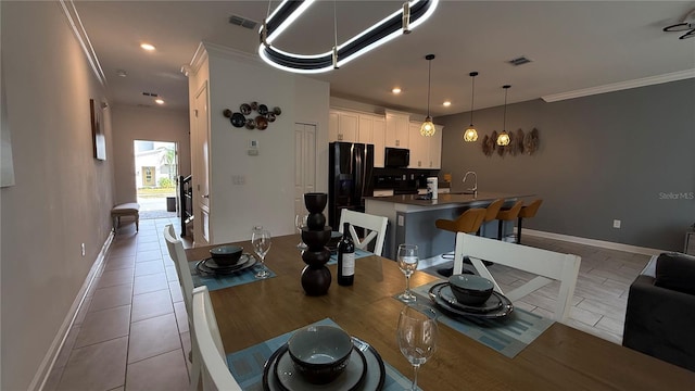 tiled dining room with sink and crown molding