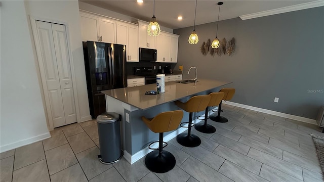 kitchen with a center island with sink, decorative light fixtures, black appliances, white cabinets, and sink