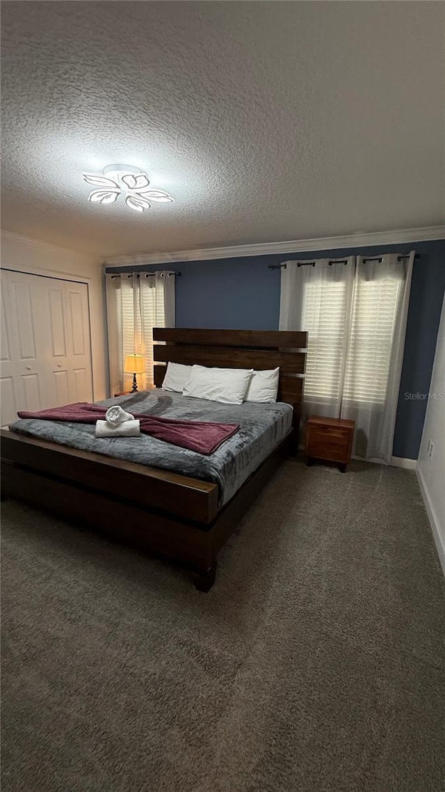 carpeted bedroom featuring a textured ceiling, a closet, ornamental molding, and multiple windows