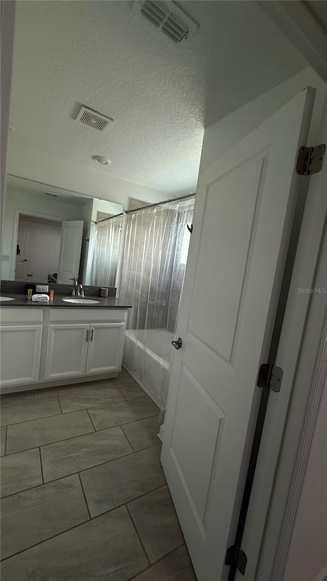 bathroom with a textured ceiling, vanity, and shower / washtub combination