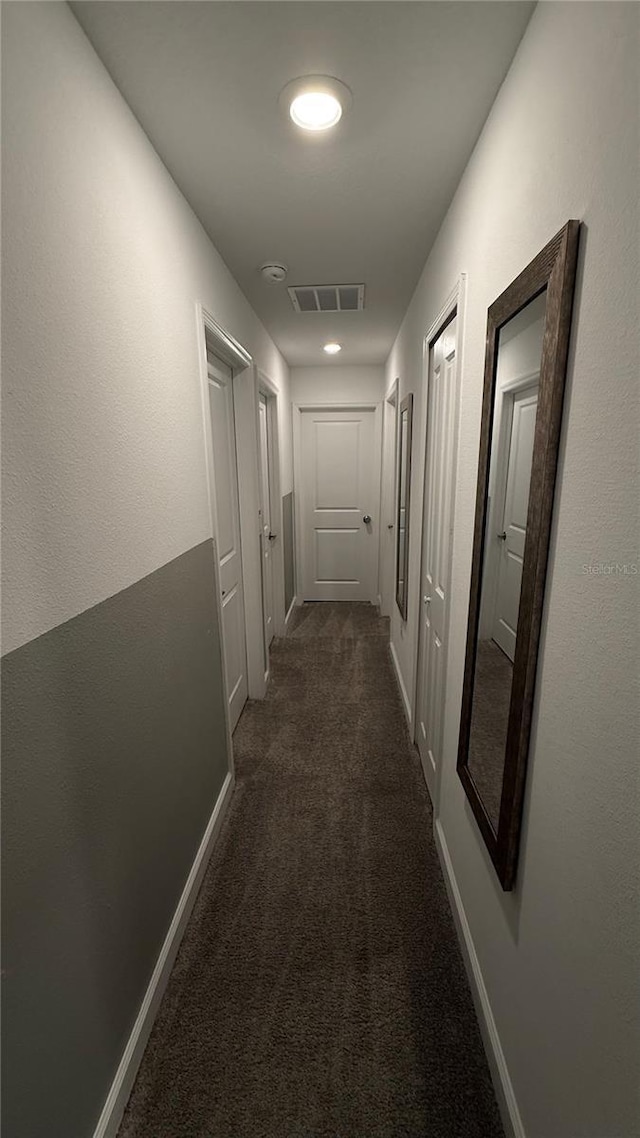 hall featuring dark colored carpet