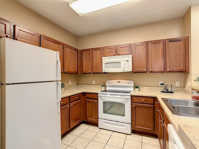 kitchen with light tile patterned floors, white appliances, and sink