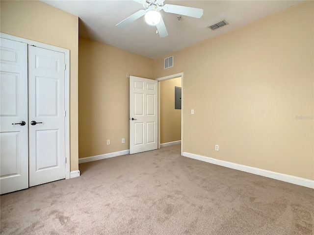 unfurnished bedroom with light carpet, electric panel, a closet, and ceiling fan