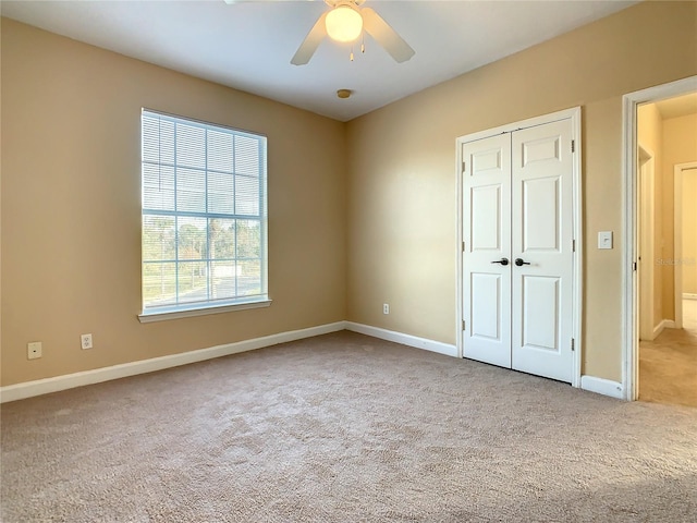 unfurnished bedroom with ceiling fan, light carpet, and a closet