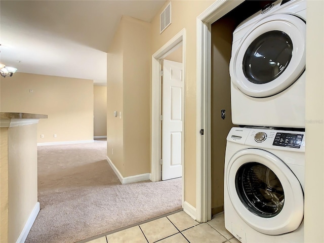 washroom featuring a notable chandelier, light tile patterned floors, and stacked washer and clothes dryer