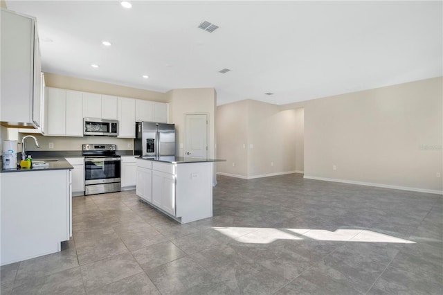 kitchen with white cabinets, a center island, stainless steel appliances, and sink