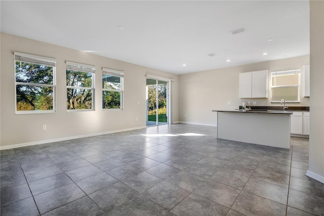 unfurnished living room featuring tile patterned floors, plenty of natural light, and sink