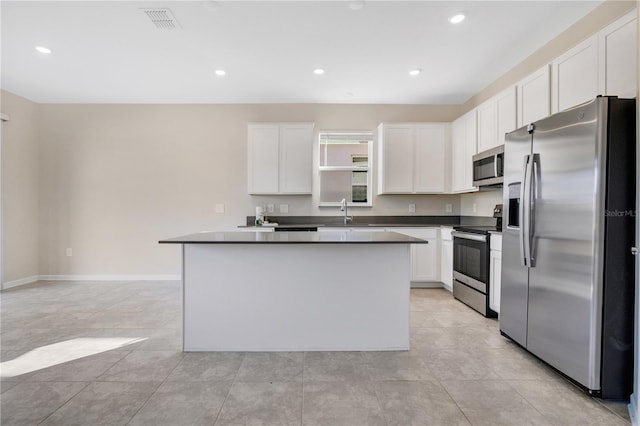 kitchen featuring white cabinetry, a center island, sink, light tile patterned floors, and appliances with stainless steel finishes