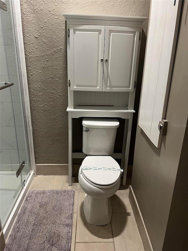 bathroom featuring tile patterned floors, an enclosed shower, and toilet