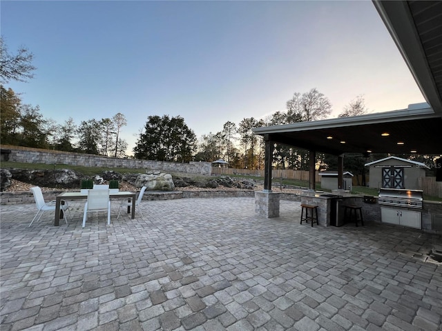 patio terrace at dusk with area for grilling and a storage shed