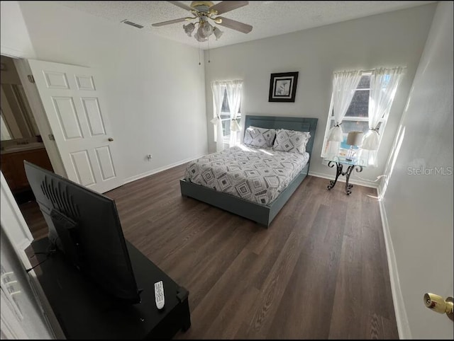 bedroom with ceiling fan, dark wood-type flooring, and a textured ceiling