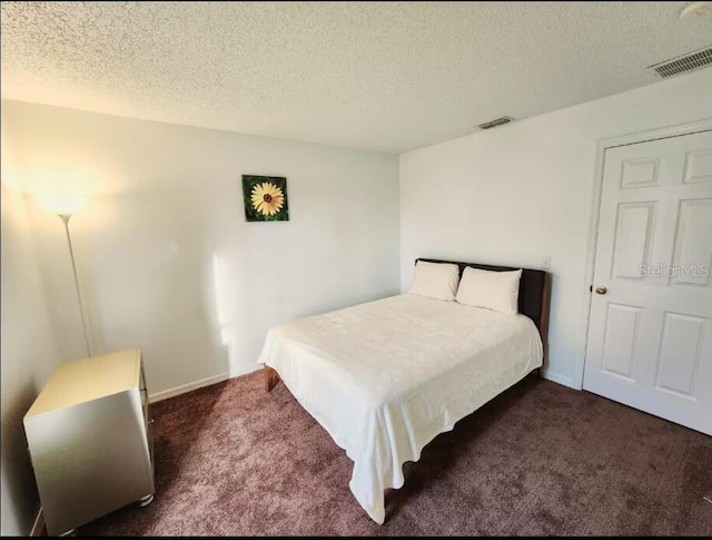 bedroom featuring dark carpet and a textured ceiling