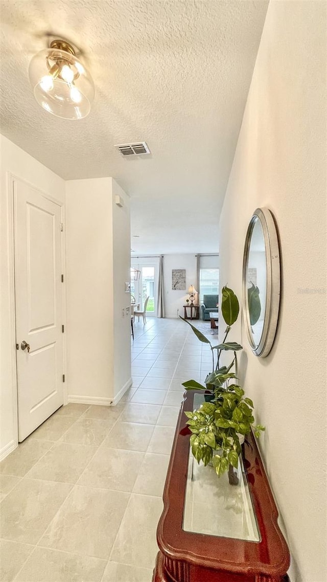 hall with light tile patterned floors and a textured ceiling