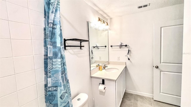 bathroom with tile patterned flooring, vanity, a textured ceiling, and toilet