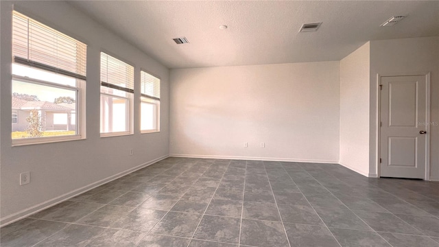 tiled empty room with a textured ceiling