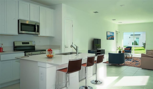 kitchen with white cabinets, sink, stainless steel appliances, and an island with sink