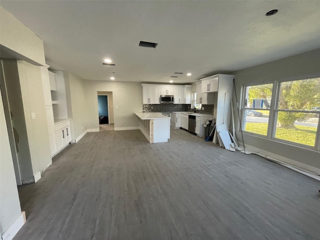 kitchen featuring sink, tasteful backsplash, hardwood / wood-style floors, white cabinets, and appliances with stainless steel finishes