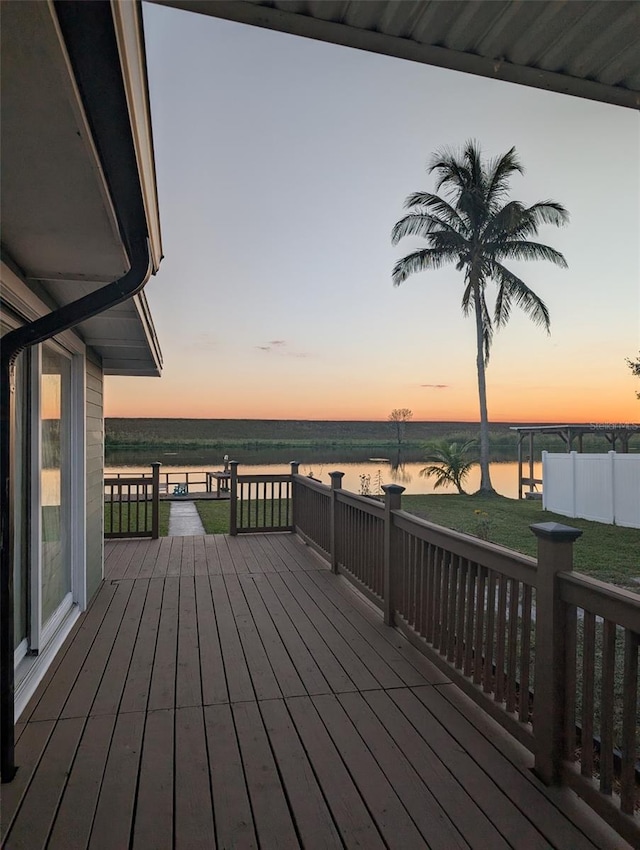 deck at dusk with a yard and a water view