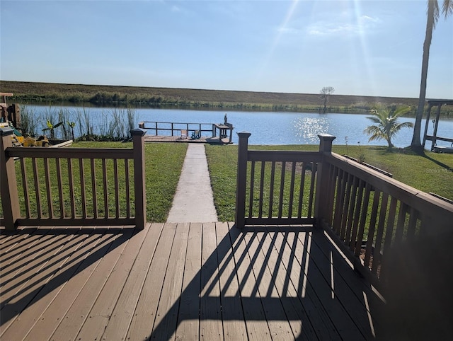 view of dock with a yard and a deck with water view