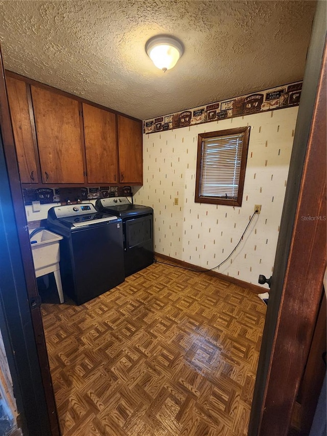 clothes washing area featuring cabinets, a textured ceiling, washer and clothes dryer, and dark parquet floors