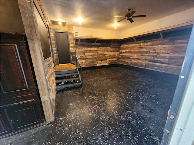 empty room with ceiling fan and wood walls