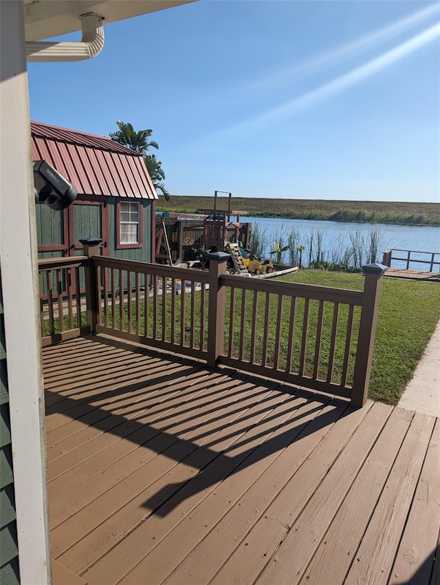 wooden deck with a yard, a water view, and an outdoor structure