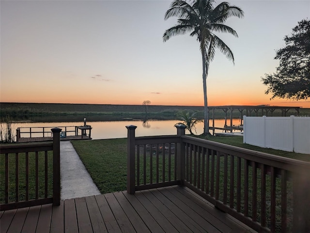 deck at dusk with a water view and a yard