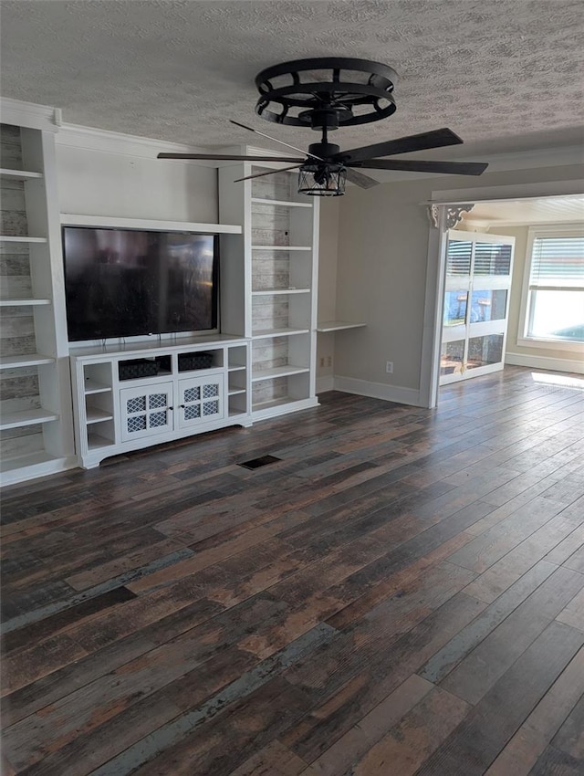 unfurnished living room featuring ceiling fan, dark hardwood / wood-style flooring, built in shelves, and a textured ceiling