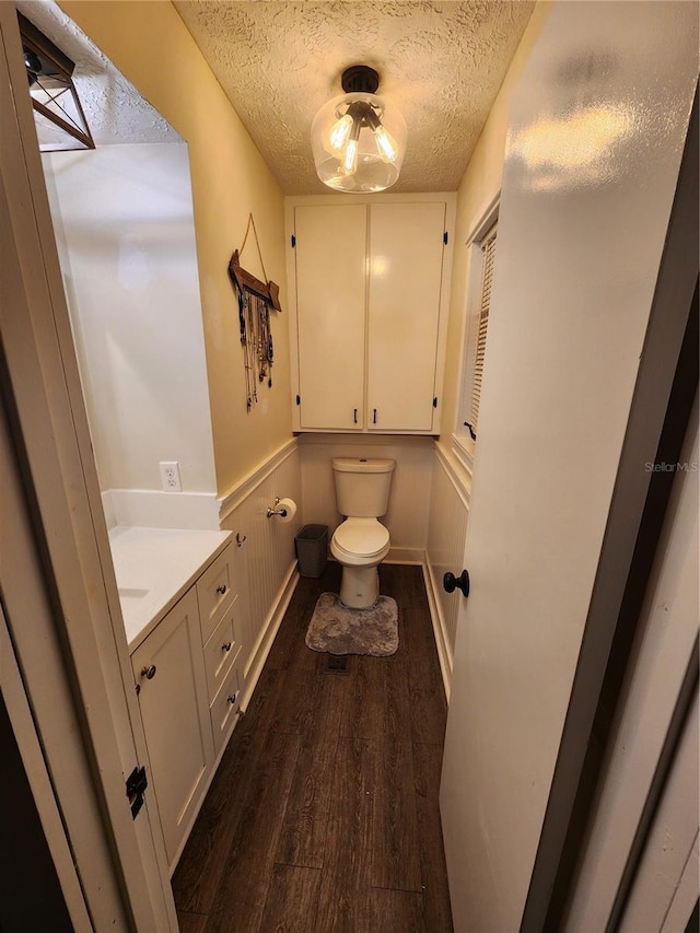 bathroom with hardwood / wood-style floors, toilet, vanity, and a textured ceiling