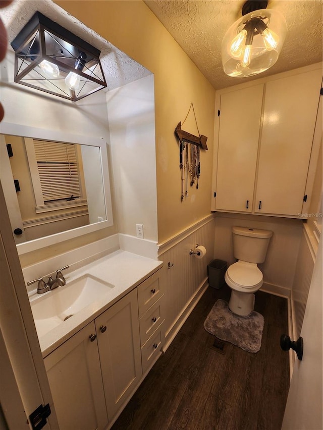 bathroom with vanity, toilet, hardwood / wood-style floors, and a textured ceiling