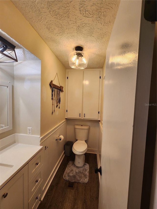 bathroom with a textured ceiling, hardwood / wood-style flooring, toilet, and vanity