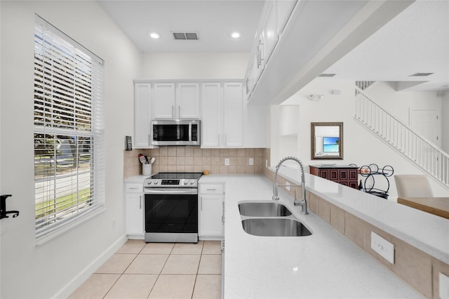 kitchen featuring decorative backsplash, stainless steel appliances, sink, white cabinetry, and light tile patterned flooring