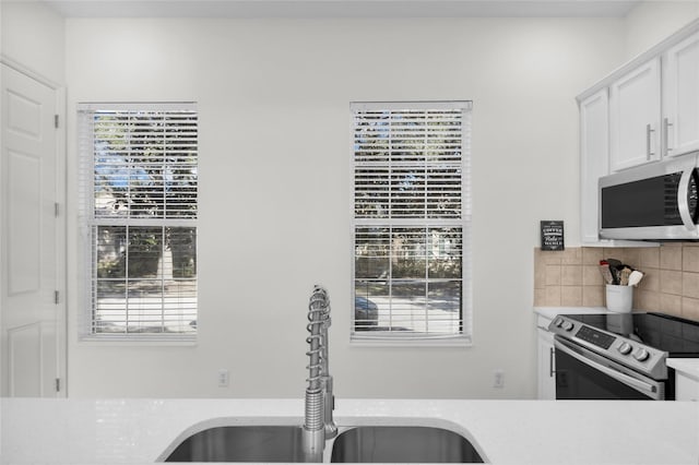 kitchen with sink, plenty of natural light, white cabinets, and appliances with stainless steel finishes