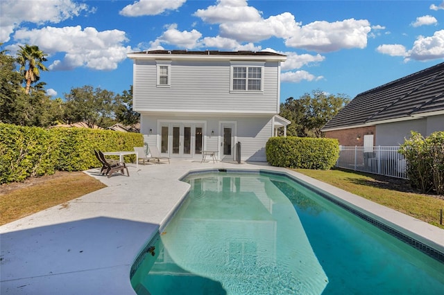 rear view of house with a fenced in pool, a patio area, and french doors