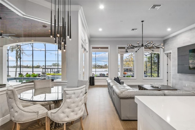 interior space with ornamental molding, ceiling fan with notable chandelier, and light hardwood / wood-style floors