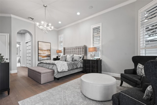 bedroom featuring dark hardwood / wood-style flooring, crown molding, and an inviting chandelier