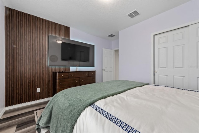 bedroom featuring a closet, wood-type flooring, and a textured ceiling