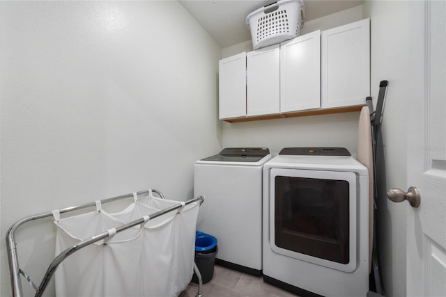 laundry room with light tile patterned flooring, cabinets, and washing machine and clothes dryer