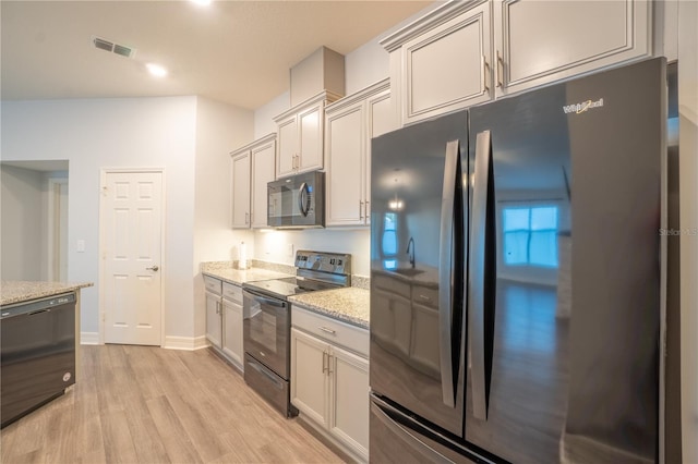 kitchen with light stone countertops, black appliances, and light hardwood / wood-style floors