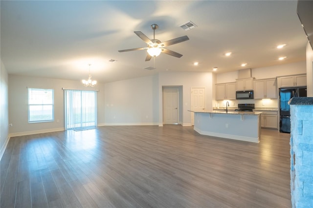 kitchen with sink, black appliances, wood-type flooring, a center island with sink, and decorative light fixtures