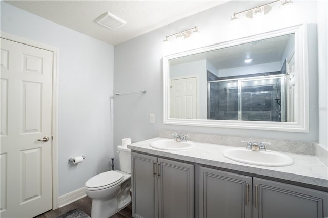 bathroom with vanity, a textured ceiling, hardwood / wood-style flooring, toilet, and a shower with shower door