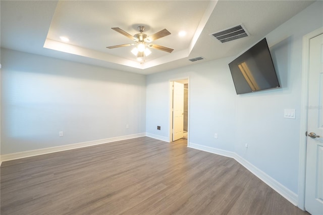 empty room with a raised ceiling, ceiling fan, and hardwood / wood-style floors