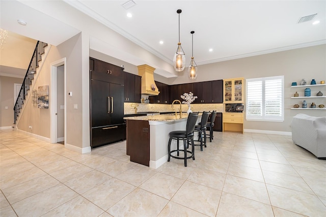 kitchen with a breakfast bar area, decorative backsplash, built in refrigerator, and crown molding