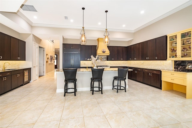 kitchen featuring a breakfast bar area, decorative backsplash, and dark brown cabinets