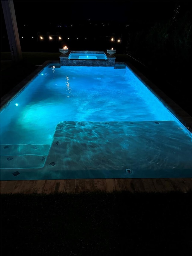 pool at twilight with an in ground hot tub